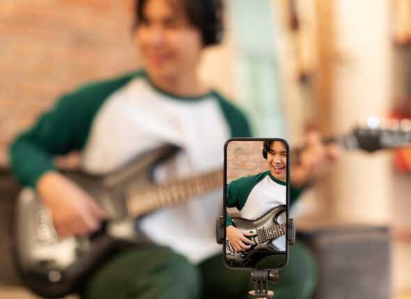 Smartphone Filming Japanese Musical Blogger Guy Playing Electric Guitar Indoors