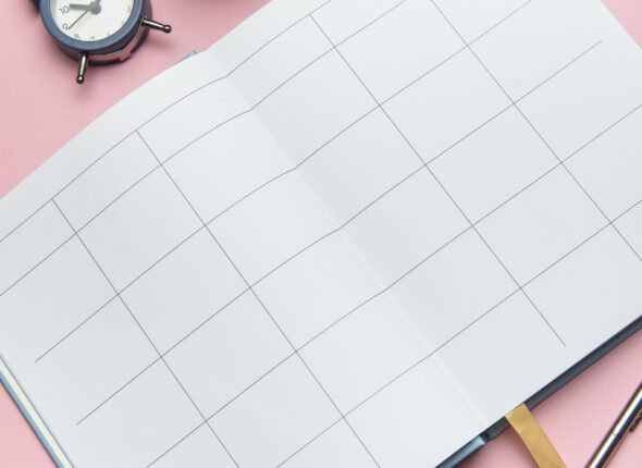 Open notebook, pen, alarm clock, and cactus on pink background s